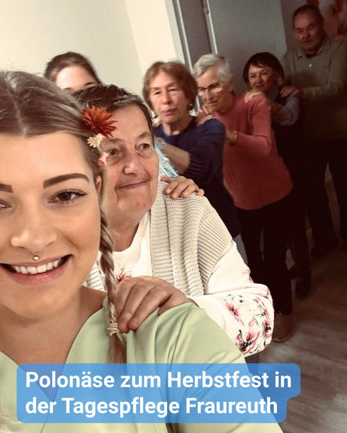 Pflegekraft tanzt eine Polonäse mit ihren Seniorinnen und Senioren durch die Einrichtung. Bildbeschriftung: „Polonäse zum Herbstfest in der Tagespflege Fraureuth”