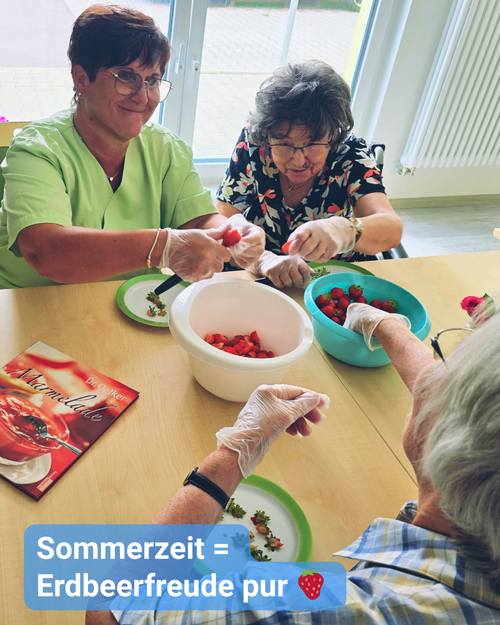 Drei Personen, darunter eine Pflegekraft, bereiten Erdbeeren am Tisch zu. Text: 'Sommerzeit = Erdbeerfreude pur'.